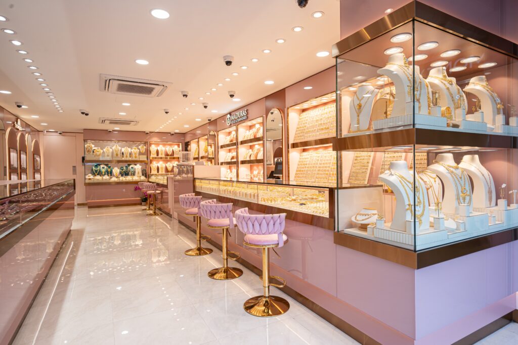 The design features a cohesive colour palette dominated by soft dusty pink walls and counters, contrasted with gleaming gold accents and highly polished, reflective white tiled flooring.
